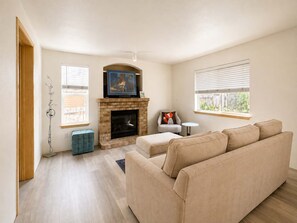 A living room with a fireplace, a sofa, a small table, and a chair. - Quiet Renton 3BR House near Valley Medical Ctr (Renton)