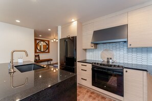 Eine moderne Küche mit schwarzem Arbeitsplatz, Edelstahlgeräten und Holzschränken.
