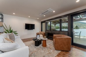 Ein modernes Wohnzimmer mit Kamin, einer Couch, einem Couchtisch und einem großen Fenster mit Blick auf ein Gewässer.