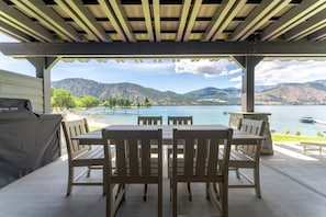 An outdoor patio with a table and chairs, overlooking a lake and mountains. - Lakefront Condo B1  Pool in Wapato Point Chelan (Manson)
