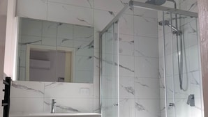 A modern bathroom with a glass-enclosed shower, a white sink, and a marble-tiled wall. - Sleep4 NewVilla 1BR 2Bath Parking Near Parramatta (South Wentworthville)