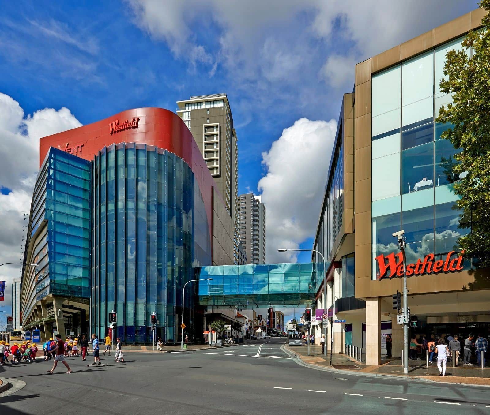 A modern building with a prominent red sign and a glass facade, likely a hotel or commercial property.