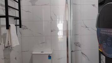 A modern bathroom with a toilet, a shower enclosure, and a towel rack.