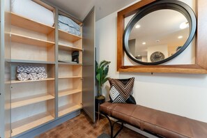 A room with a bench, a mirror, and a shelving unit with folded blankets. - Lakefront Condo B2  Pool in Wapato Point Chelan (Manson)