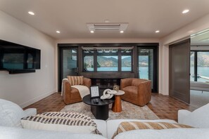 Ein modernes Wohnzimmer mit Kamin, Ledersofas, einem Couchtisch und einem an der Wand befestigten Fernseher.