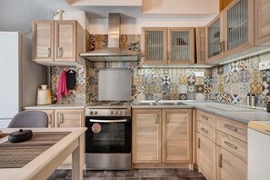A kitchen with wooden cabinets, a stainless steel stove, and a tiled backsplash. - Country House 'Rahati Suite' with Private Terrace and Wi-Fi (Tzermiado)