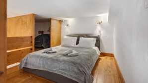 Une chambre à coucher de taille modeste, comprenant un lit, une armoire en bois et un petit coin salon.