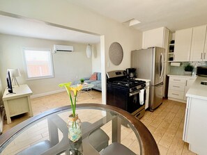 Eine moderne Küche mit Herd, Kühlschrank und Mikrowelle. Ein Esstisch mit Blumen in einer Vase steht daneben.