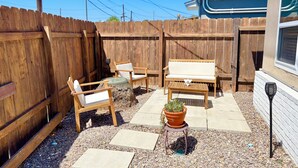 Un jardin avec une clôture en bois, des meubles d’extérieur, une plante en pot et un espace patio.