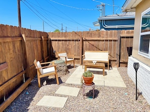 Ein Garten mit Holzlattenzaun, Gartenmöbeln, einem Blumentopf und einer Terrassenfläche.