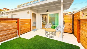 A modern house with a covered patio, a wooden fence, and a green lawn. - Perfect 4 Families, Walk To Beach, Roof-Top Patio! (Oxnard)