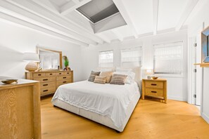 A bedroom with a large bed, wooden dresser, bedside tables, and a skylight. - Perfect 4 Families, Walk To Beach, Roof-Top Patio! (Oxnard)