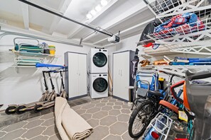 Ein Waschraum mit Waschmaschine, Trocknern und einer Bügelgelegenheit.