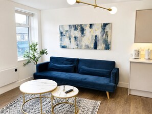 Una sala de estar moderna con un sofá azul, una mesa de centro redonda y un cuadro en la pared.