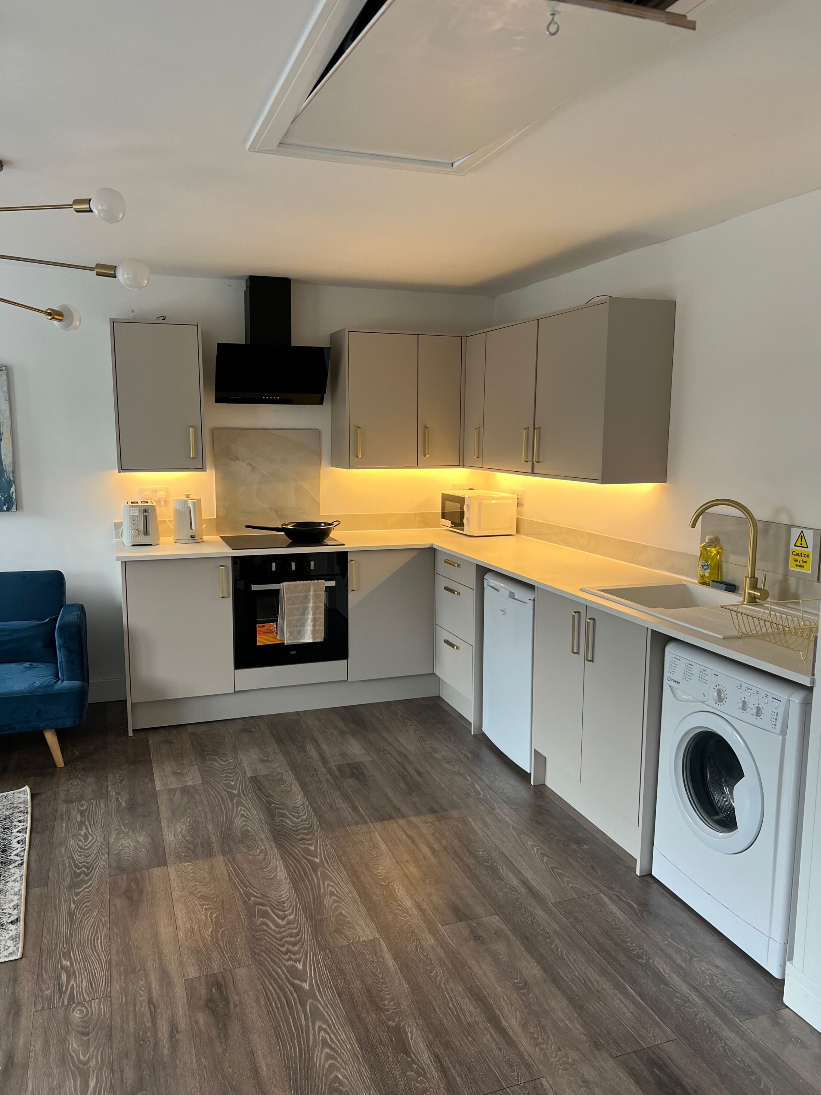 A compact kitchen with a built-in oven, dishwasher, and washing machine.