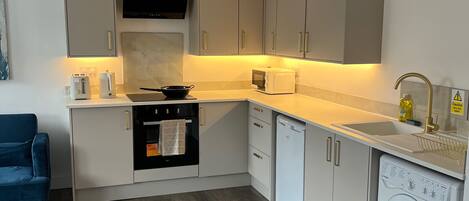 A compact kitchen with a built-in oven, dishwasher, and washing machine.