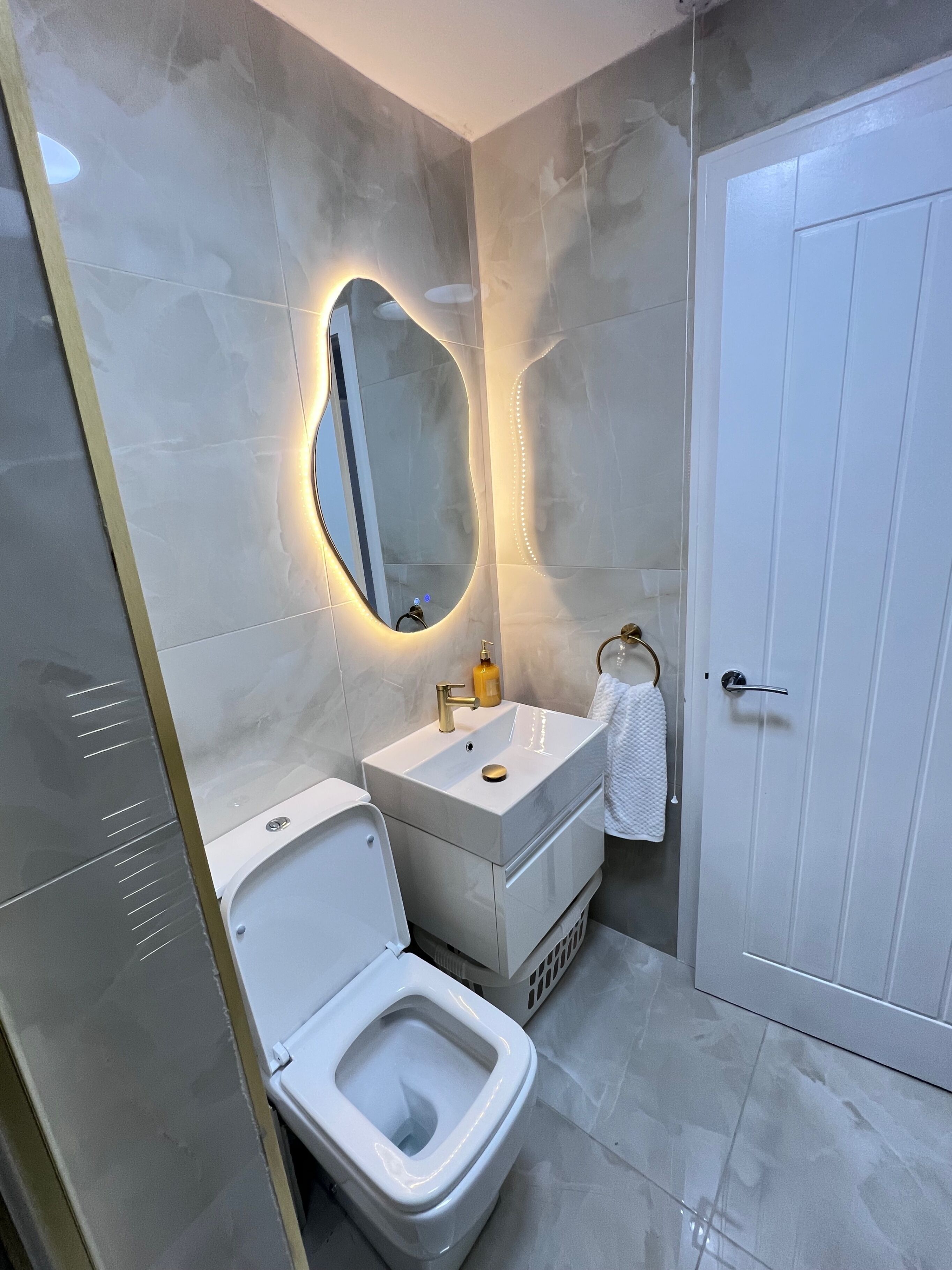 A modern bathroom with a toilet, sink, and mirror.