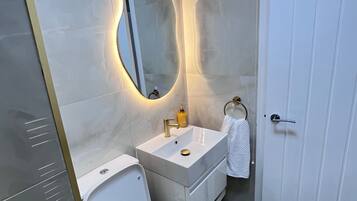 A modern bathroom with a toilet, sink, and mirror.