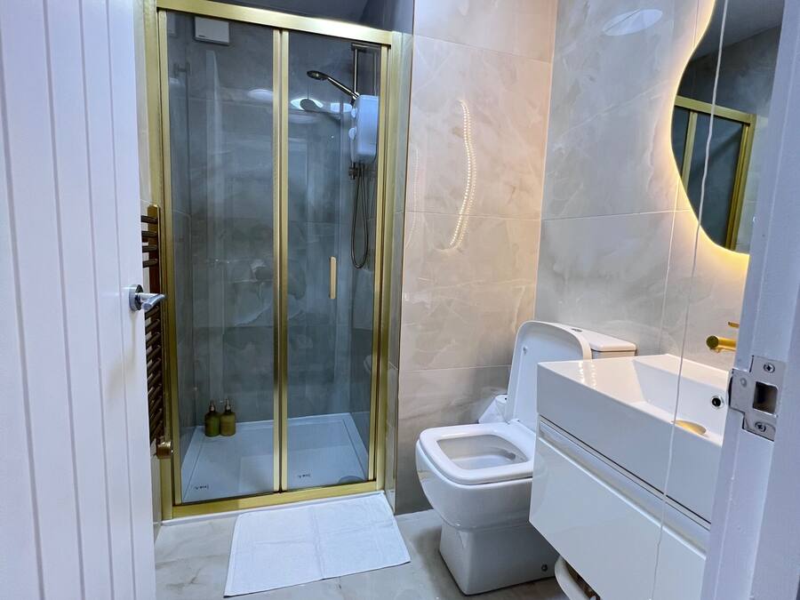 Ein modernes Badezimmer mit einer Duschkabine, einer Toilette und einem Waschtisch mit Spiegel.