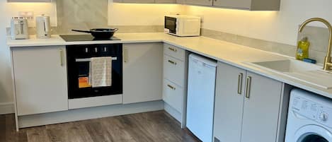A modern kitchen with a built-in oven, microwave, and dishwasher, and a washing machine in the corner.