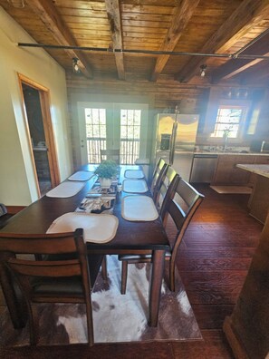 A dining area with a long wooden table, chairs, and a central plant. - New built log home designed with elegance, charm and finish with 360 vi (Arnold)