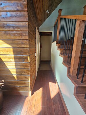 Uma escada de madeira com corrimão e uma porta que dá para um quarto.