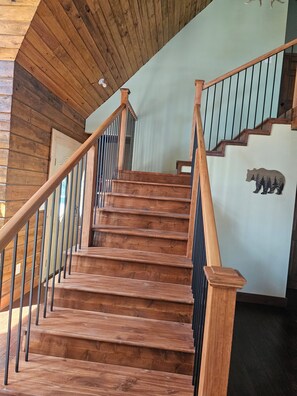A wooden staircase with a bear decoration on the wall, leading to a room with a wooden ceiling. - New built log home designed with elegance, charm and finish with 360 vi (Arnold)