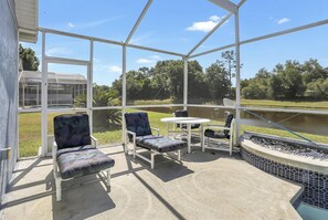 A covered patio with two chairs and a table, overlooking a body of water and greenery. - 25% Off Magical Villa with Pool (Kissimmee)