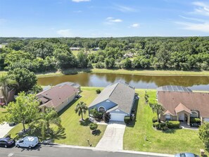 A residential area with houses, a pond, and a clear sky. - 25% Off Magical Villa with Pool (Kissimmee)