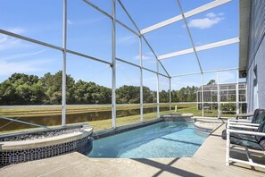 Piscina com vista para um lago e árvores, rodeada por um espaço coberto com cadeiras.