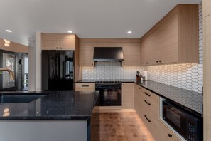 A modern kitchen with a central island, black appliances, and wooden cabinetry. - Lakefront Condo B3  Pool in Wapato Point Chelan (Manson)
