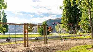 A park with swings, a wooden swing set, and a view of a lake and hills. - Lakefront Condo B4  Pool in Wapato Point Chelan (Manson)