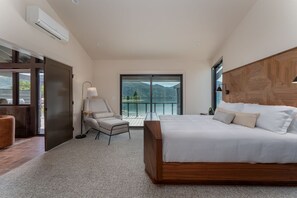 A bedroom with a large bed, a chair, a lamp, and a view of a lake through a glass door. - Lakefront Condo B4  Pool in Wapato Point Chelan (Manson)