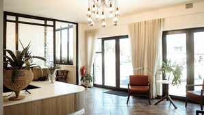 A hotel lobby with a reception desk, seating area, large windows, and a chandelier. - Railway Hotel (Wellington)