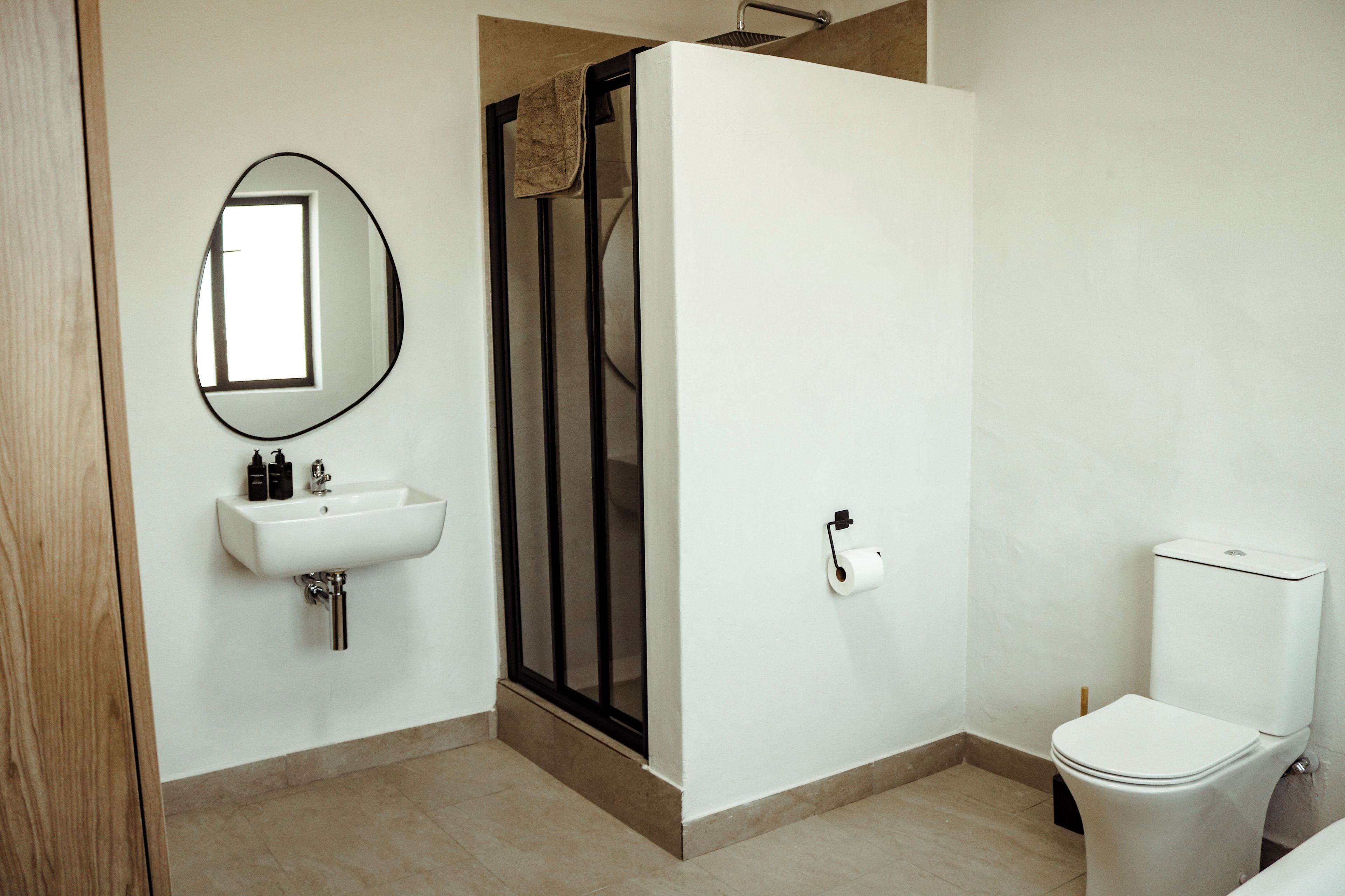 Un baño con un lavamanos blanco, inodoro y zona de ducha.
