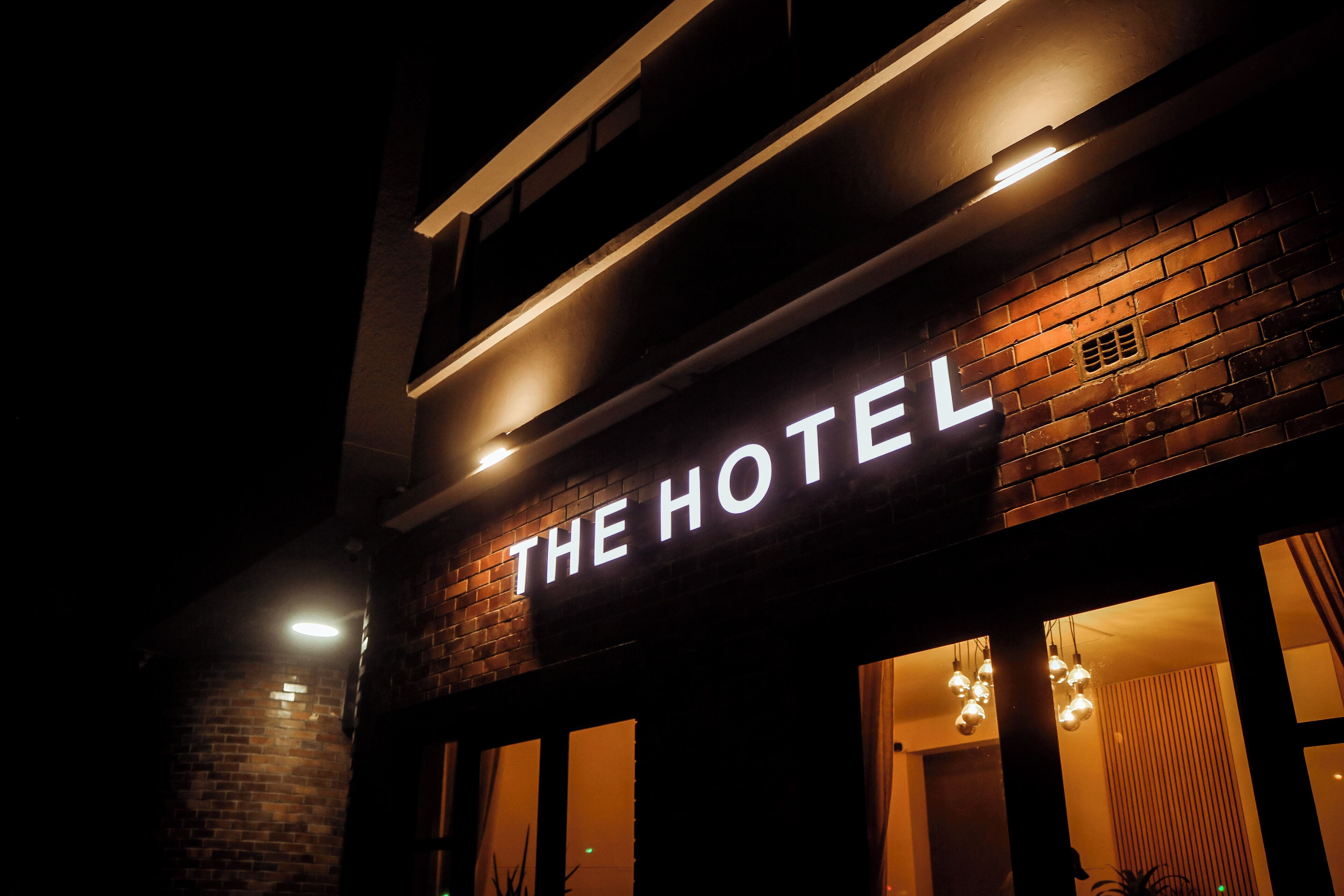 Un letrero de hotel con el nombre 'THE HOTEL' iluminado en letras blancas.
