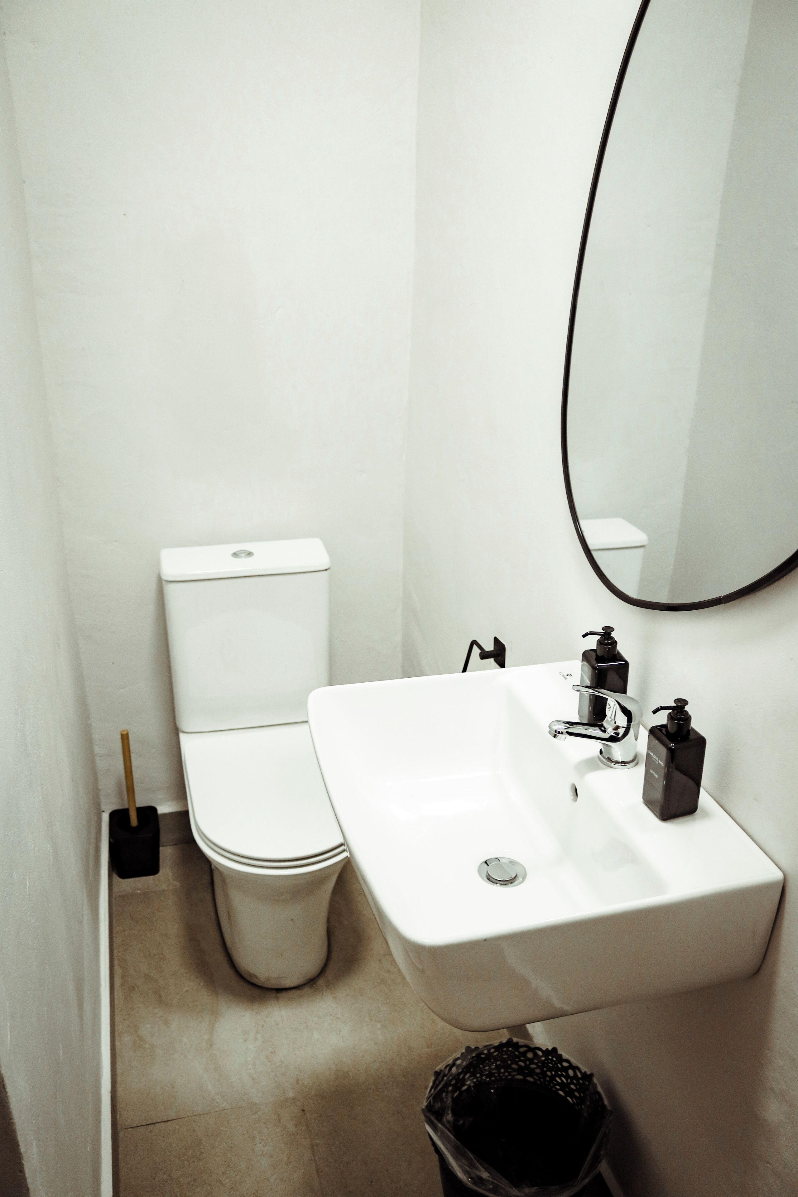 Een kleine, witte badkamer met toilet, wastafel en spiegel.