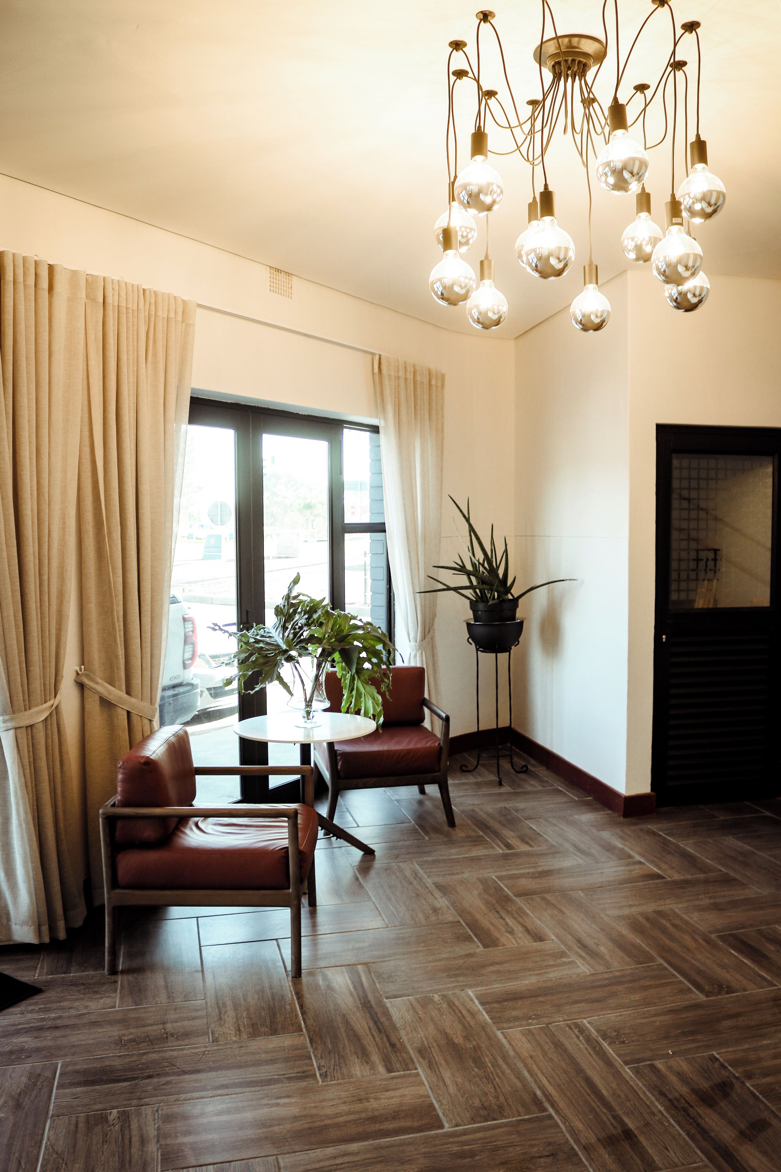 Een kamer met een eettafel, stoelen, een potplant en een hanglamp.
