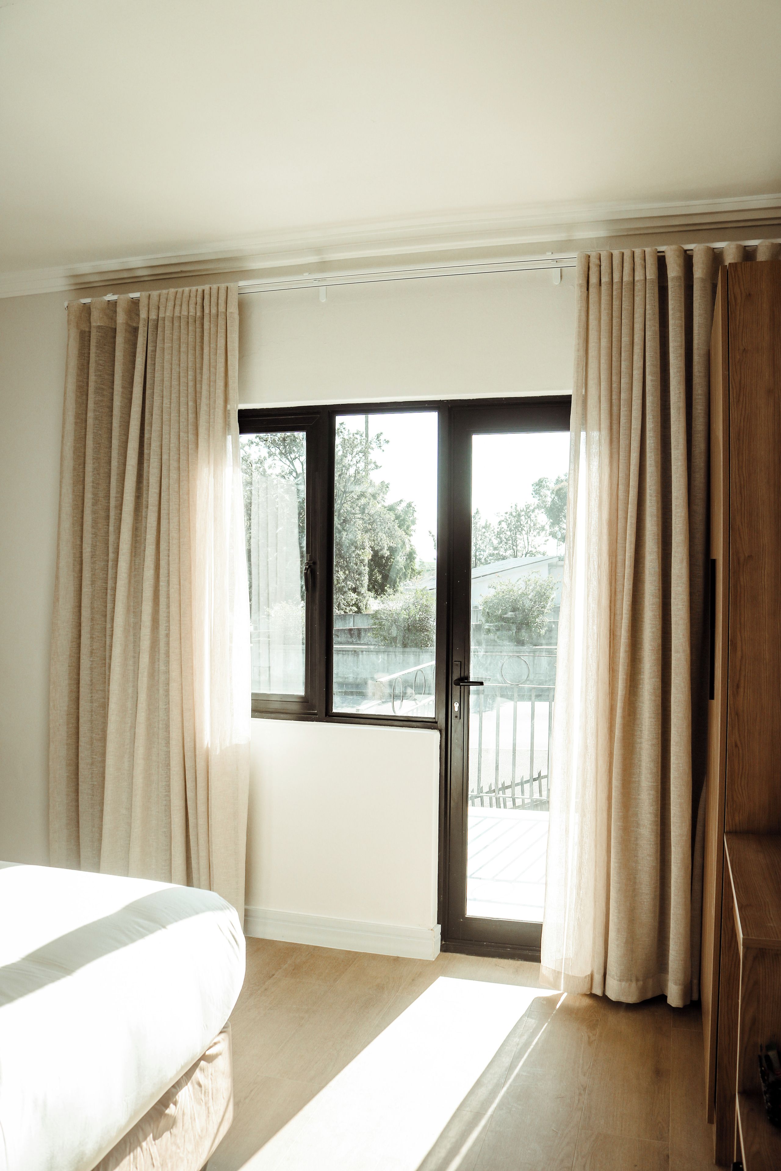 Een hotelkamer met een bed, een schuifglasdeur naar een balkon en gordijnen.