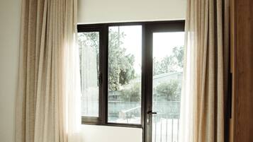 Een hotelkamer met een bed, een schuifglasdeur naar een balkon en gordijnen.