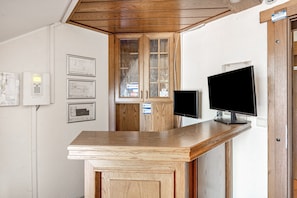 Ein Empfangstresen mit Flachbildfernseher, Holzausstattung und gerahmten architektonischen Plänen an der Wand.