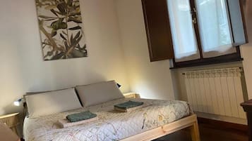 Une chambre à coucher avec un lit, une fenêtre avec des rideaux, un radiateur et une œuvre d’art accrochée au mur.