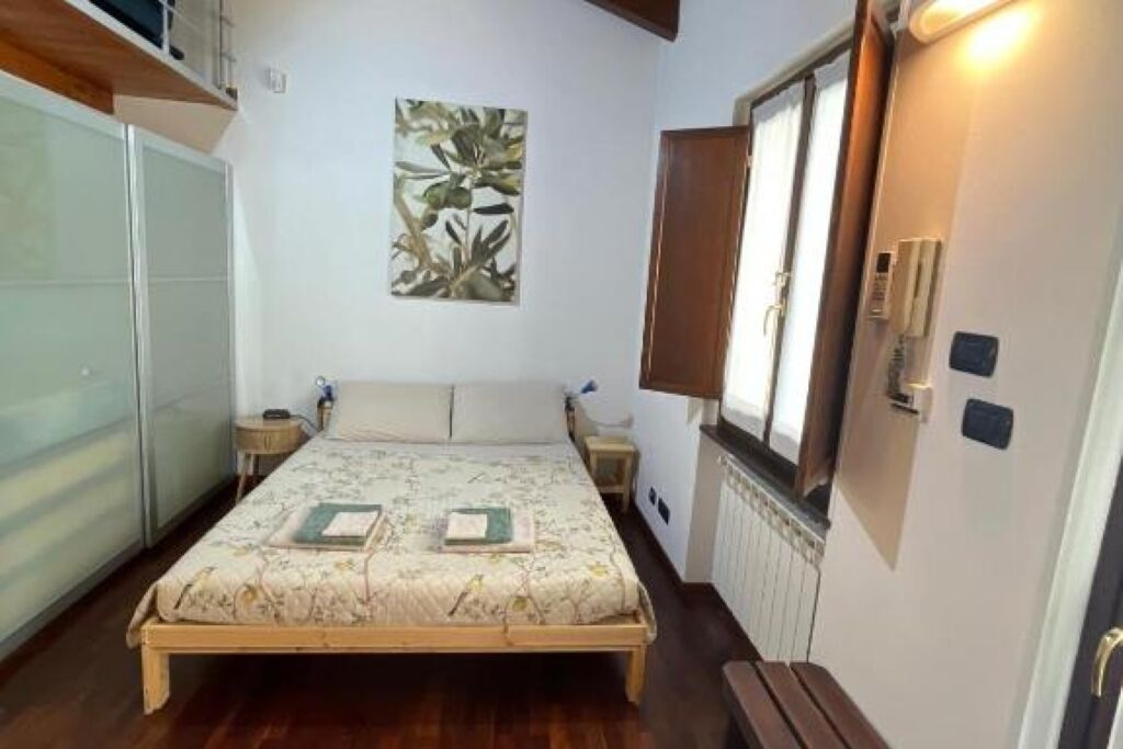 A bedroom with a bed, a nightstand, a bedside table, a radiator, and a wardrobe.