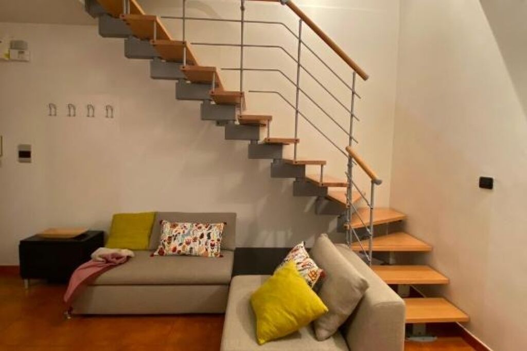 Ein modernes Wohnzimmer mit Treppe, einer Couch und einem kleinen Tisch.