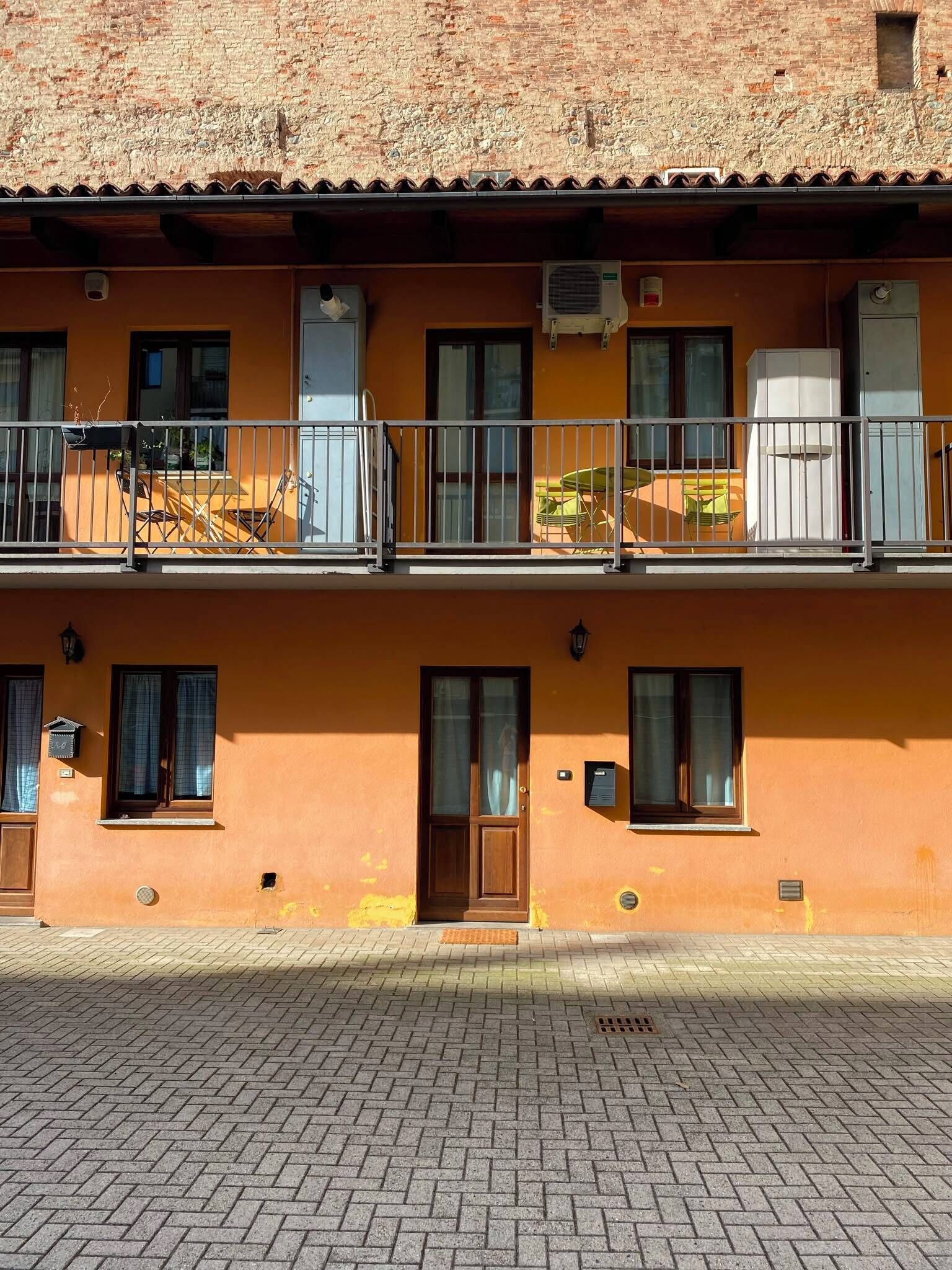 Ein zweistöckiges Gebäude mit Ziegelverkleidung, Balkonen mit Geländern und einer gefliesten Erdgeschossfassade.