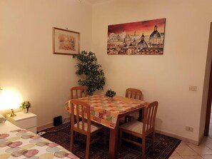 Ein Essbereich mit Tisch für vier Personen, einer Zimmerpflanze und zwei gerahmten Kunstwerken an der Wand.