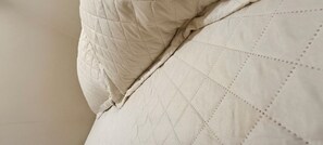 A close-up of a bed with a quilted pattern and a pillow. - Private suite with kitchen and separate entrance with parking in the city center. (Sinop)