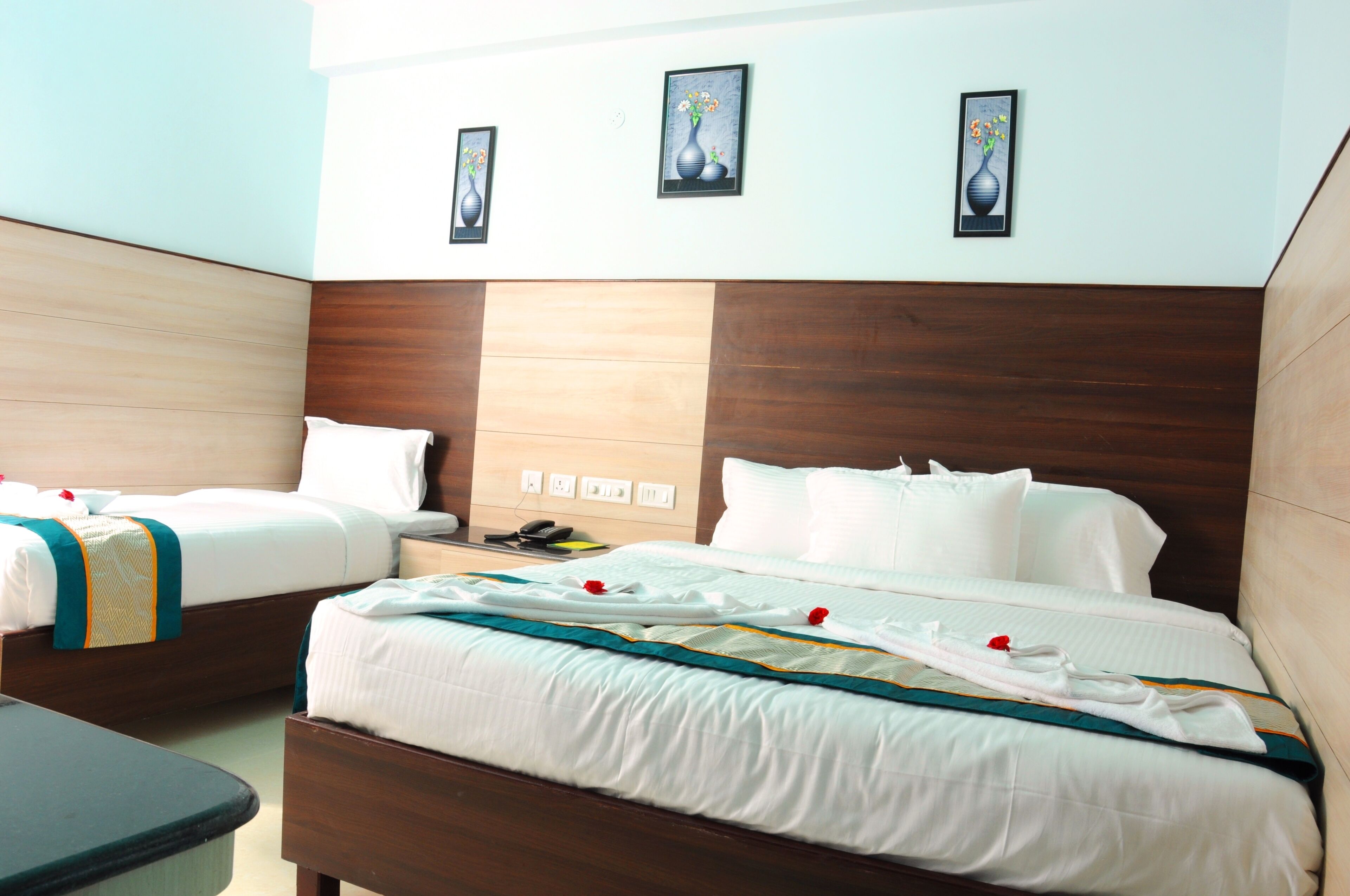 A hotel room with two beds, a wooden headboard, and three framed pictures on the wall.
