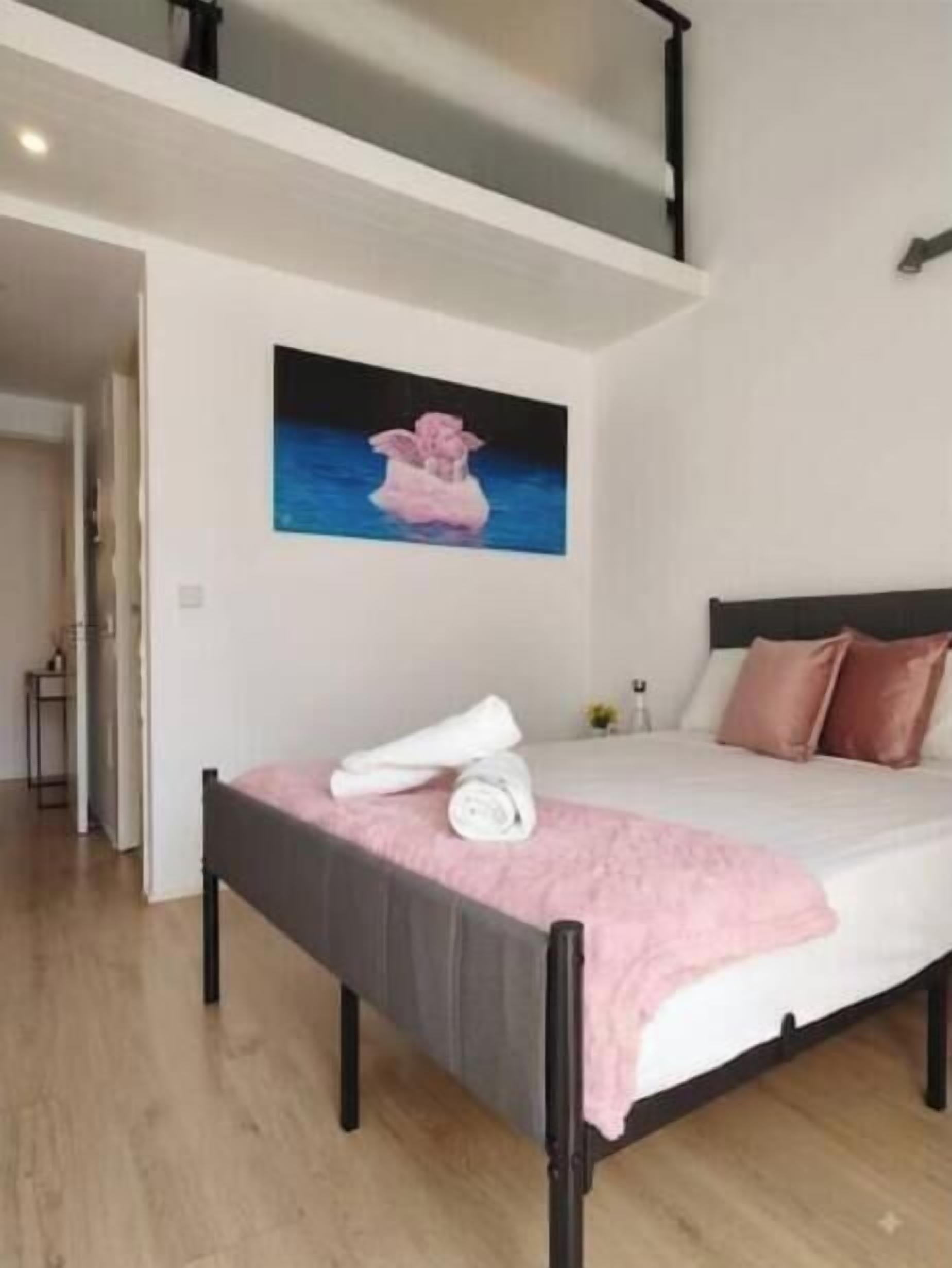 A bedroom with a bed, a painting, and a window.