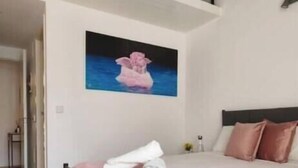 Um quarto com uma cama, um quadro e uma janela.